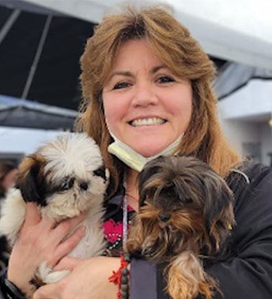 Photo of Administration, Administrative Assistant Bertha Duenes with two puppies